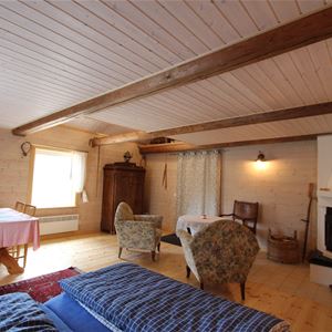 Large room with double bed,  open fire place, armchairs and a dining table. 