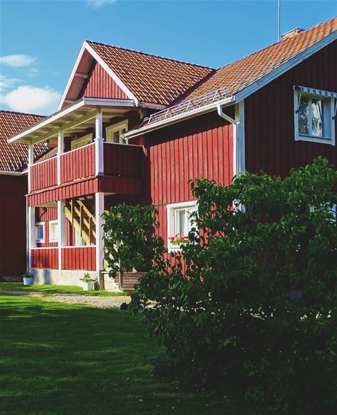 Rödmålat hus i sommarmiljö. 