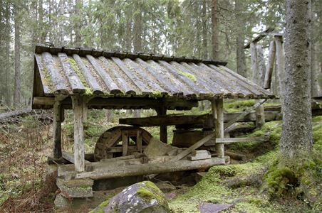 En liten byggnad med tak i skogen