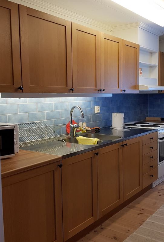 Kitchen with wooden cupboard doors and blue tiled walls. 
