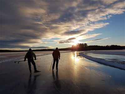 Two iceskaters on the icetrack in the sunset.