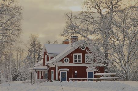 Rödmålat hus i vinterlandskap.