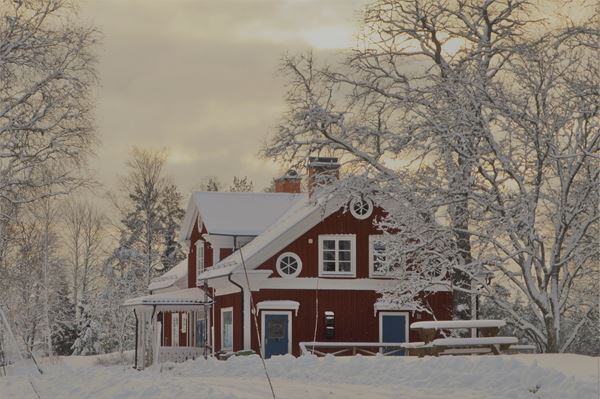 Rödmålat hus i vinterlandskap. 