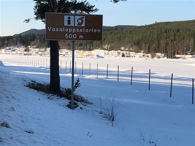 Vinterbild från ett öppet fält. Skylt med Vasaloppets start 500 m. 