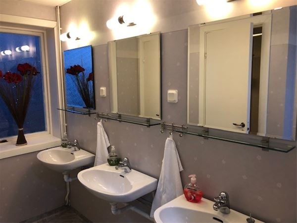 Sanitetsrum med tre tvättställ och speglar.  