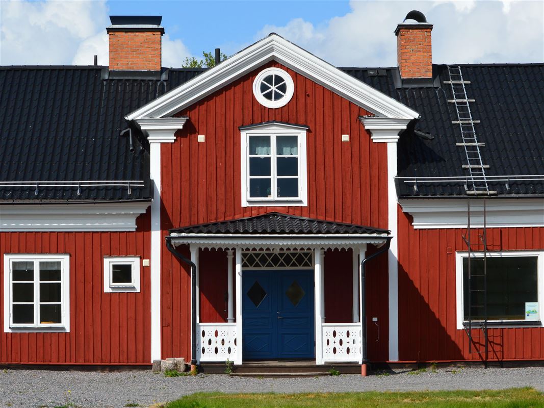 Ett stort rött hus som har blå pardörr till entrén.