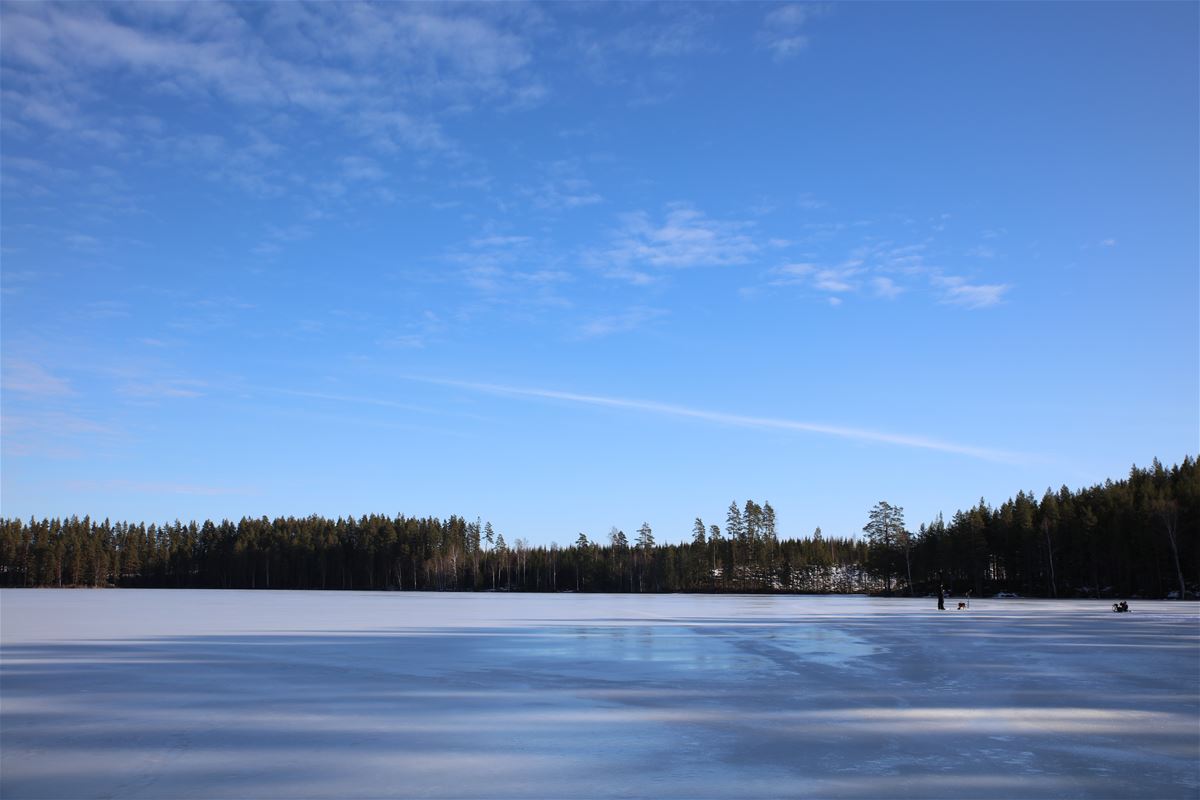 Isbeklädd sjö med blå himmel i bakgrunden.