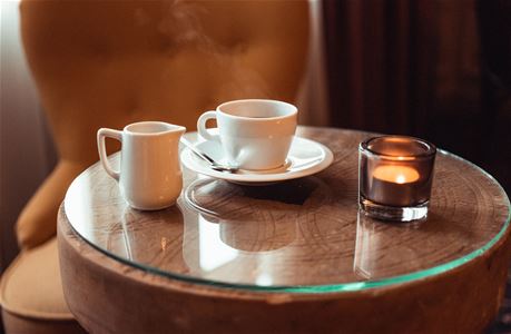 Litet runt bord med en kaffekopp och en ljuslykta. 