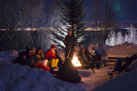 Gjester er samlet rundt bålet med snø rundt