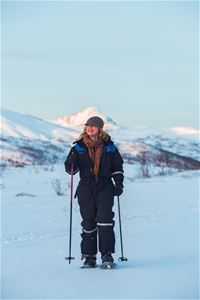 A woman snowshowing in a snowy Arctic landscape