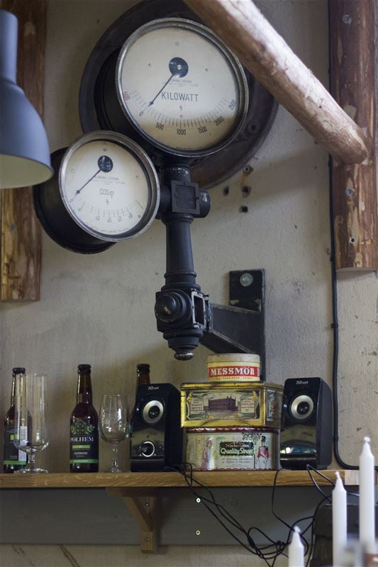 A wooden shelf with old tin cans, speakers, glasses and bottles.