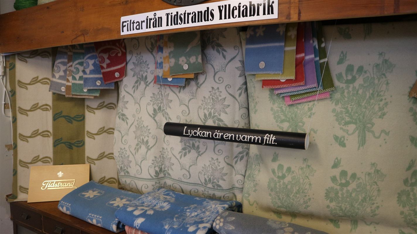 Olika filtar och tygprover, skylt med texten filtar från Tidstrands yllefabrik.