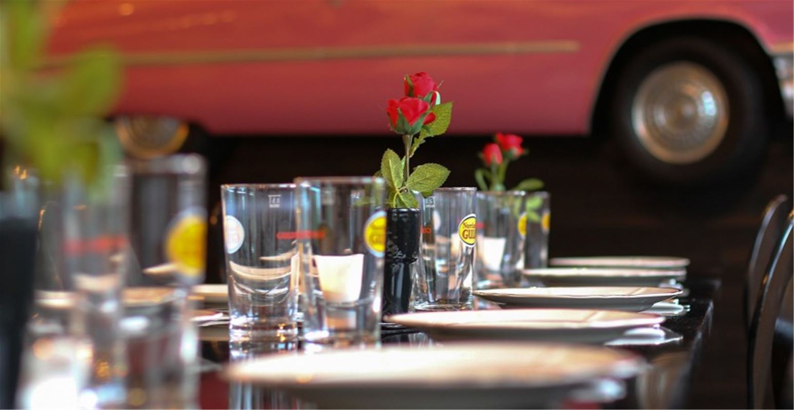 Ett dukat bord med tallrikar, glas och rosor.