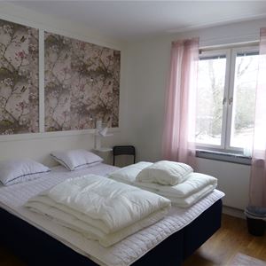 Twinbed in a pink room with a window.