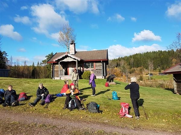 Walkers are resting on the lawn in front of a timbercottage. 