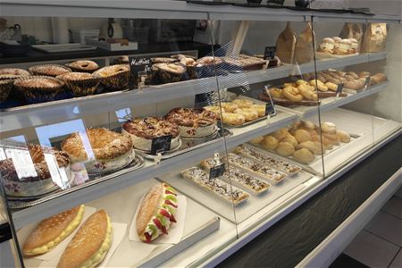 Pastries and cakes on display in a glass counter.