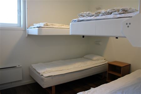 Sovrum med två enkelsängar och två nedfällbara sängar på vägg.