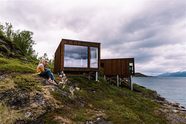  &copy; Lyngen Resort, people sitting in front of Aurora Fjord Cabin 