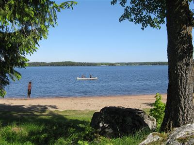 View over the beach and lake with canoe on the water.