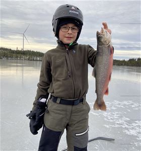 Stolt pojke visar upp sin fångst på isen.