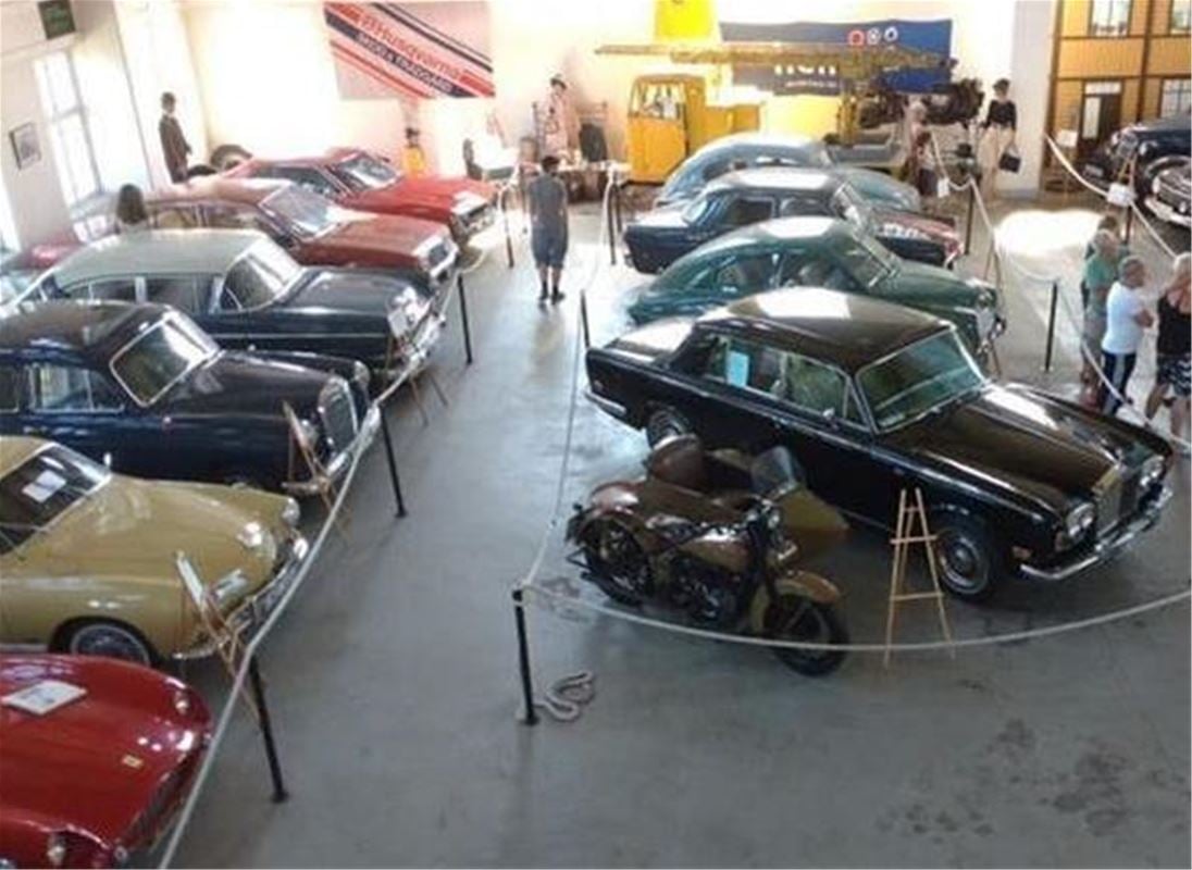 Flera gamla bilar som står uppradade i ett rum.
