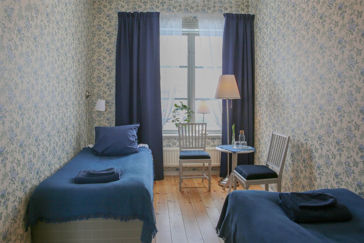 Two single beds in each corner of the room with blue bedspread and curtains.