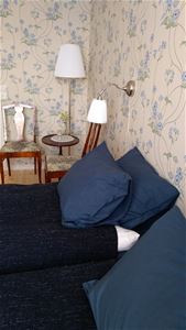 Blue pillows and two chairs and a little table and a lamp.