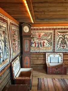 Väggmålningar med dalmotiv, dekorerade brudkistor och en fin golvklocka som är dekorerad.