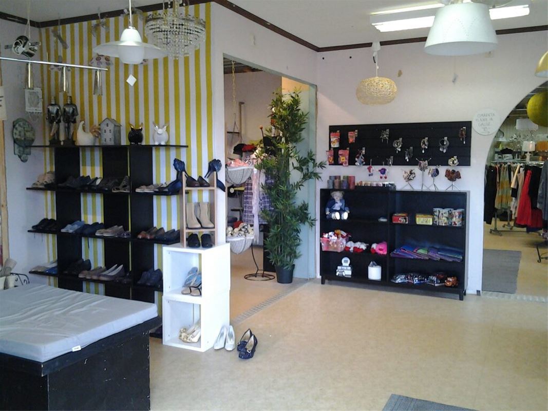 Interiörbild från butiken, närmast en gul och vitrandig vägg mot den svarta och vita hyllor med produkter, fler hyllor med produkter och kläder på galgar längre in i butiken.
