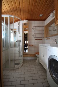Badrum med dusch, toa och tvättmaskin.