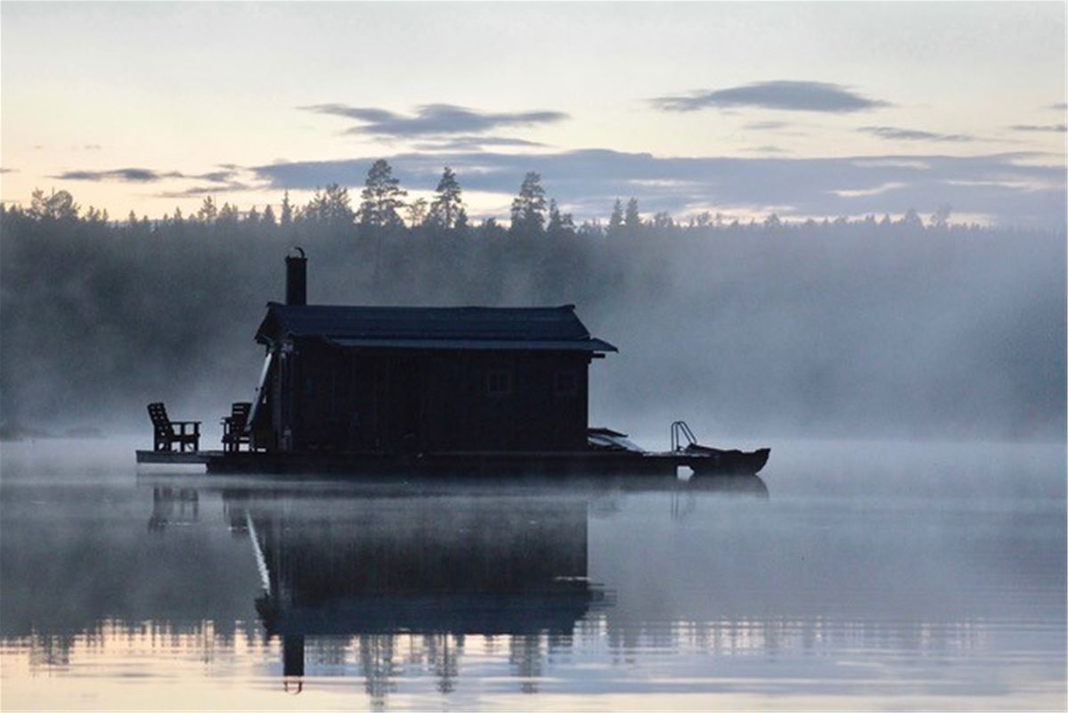 Husbåt  som glider fram på sjön i dimman.