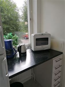 Köksbänk med kaffebryggare, vattenkokare och mikrovågsugn.