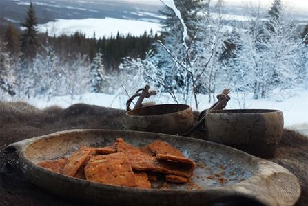 A wooden bowl with food in and white nature and forest in the background.