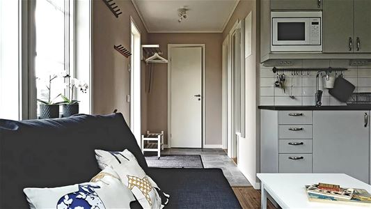 Hall intill köket där även en soffa med bord står placerad.