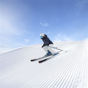 downhill skier on the piste, blue sky, blue sky.
