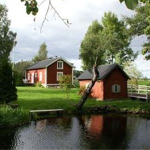 Rött hus med mindre gårdshus i närheten av vatten