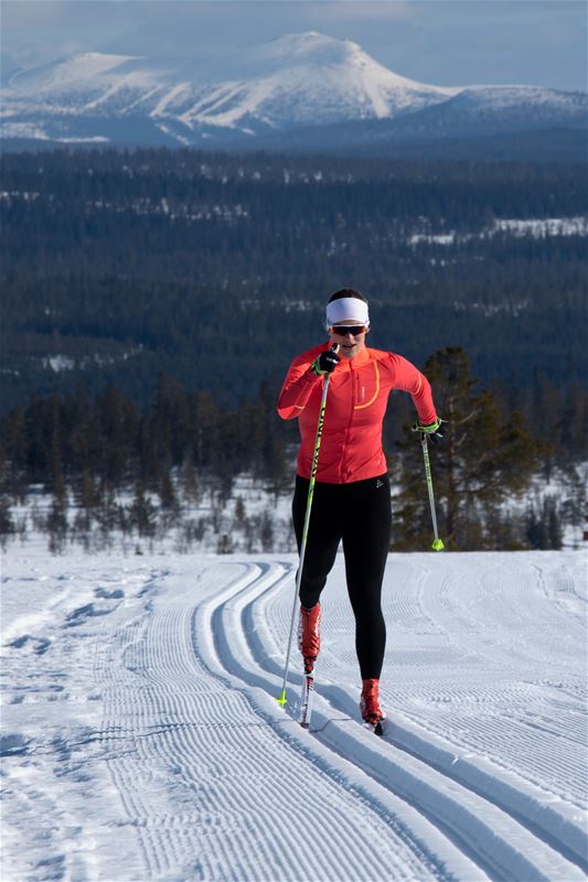 Cross-country skier classic style with mountain in the background.