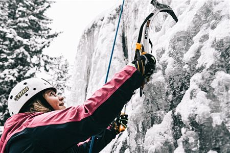 Woman climbs up an ice wall.