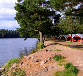 Röda camping stugor längs vattnet.