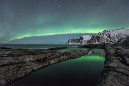 Northern lights above sea and mountains