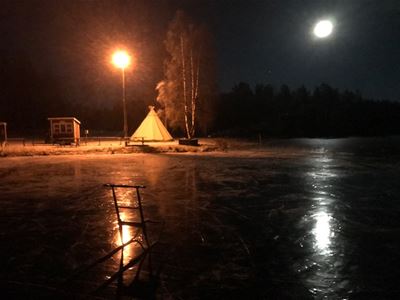 En spark på isen och en kåta invid Öjesjön i månsken. 