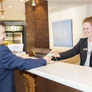 A man in a suit receives a key card from the receptionist.