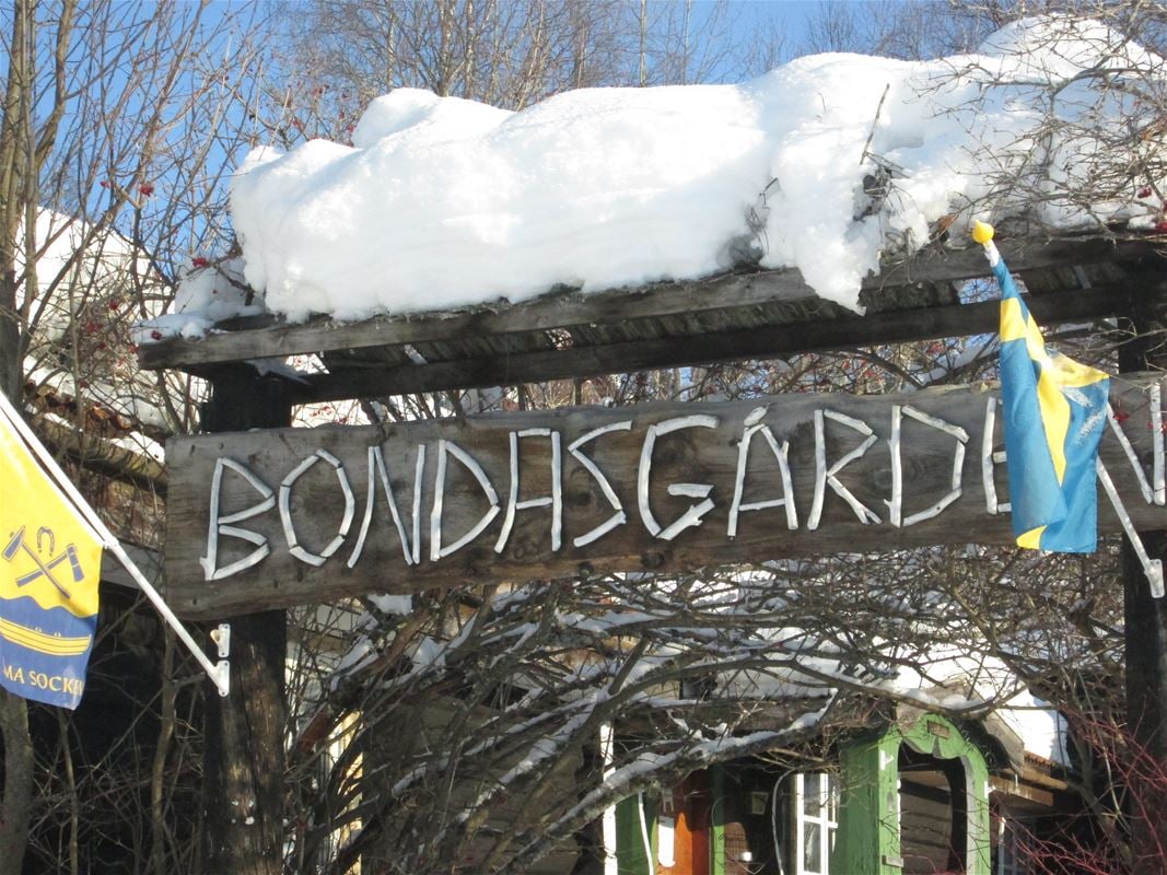 Träskylt med namn Bondasgården ovan entren. 