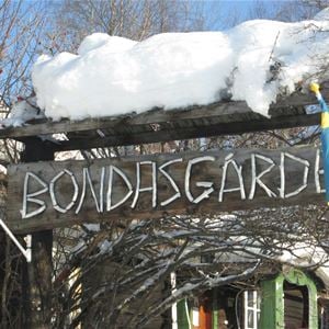 Träskylt med namn Bondasgården ovan entren. 