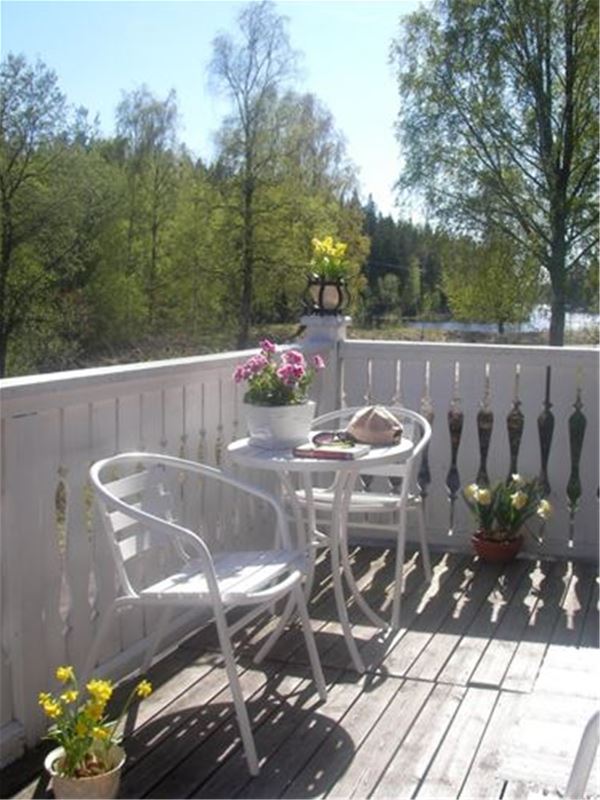 En liten balkong inrett med bord. stolar och blomkrukor.