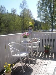 En liten veranda med två vita stolar och ett runt bord. 