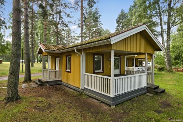 Yellow camping cottage surrounded by trees. 