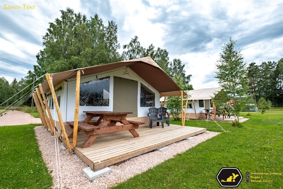 Glampingtent with picnic table under roof.