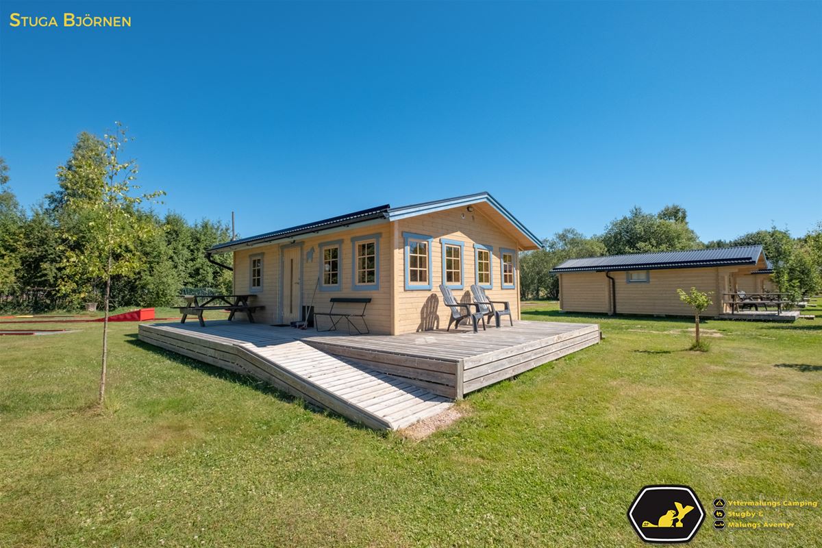 Yellow painted timber cottages with blue window linings and a ramp to the terrace of the first house. 