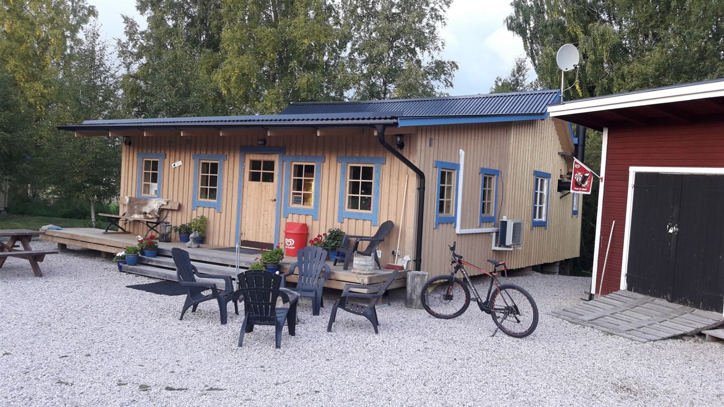 Yellow house with some outdoor furniture outside the house on the gravel floor.